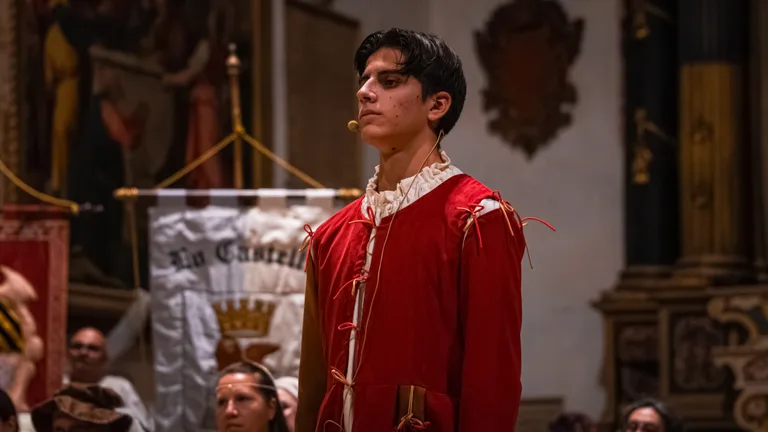 Ritratto di un giovane attore in costume rosso con il microfono