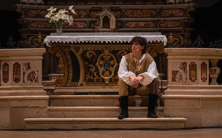Un giovane attore in costume siede sui gradini davanti all'altare della Cattedrale