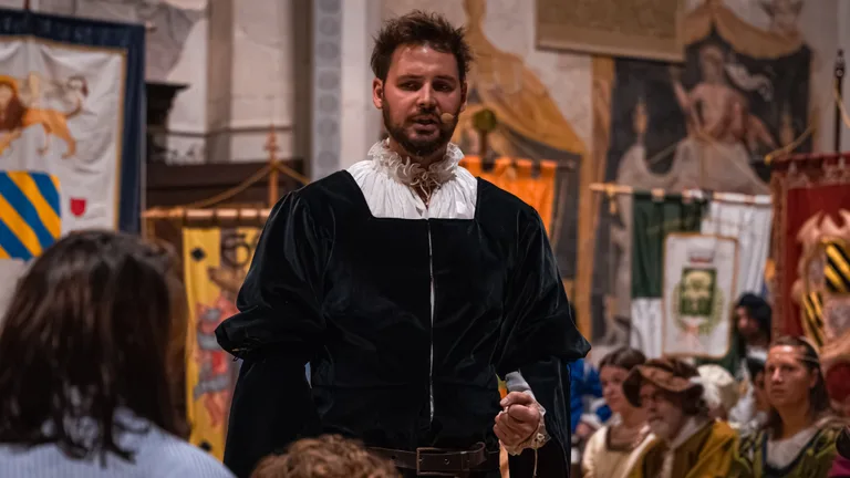 Primo piano di un attore in costume nero con il microfono